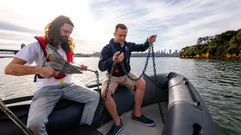 Two men handling anchor and chain on inflatable boat Sydney Harbour