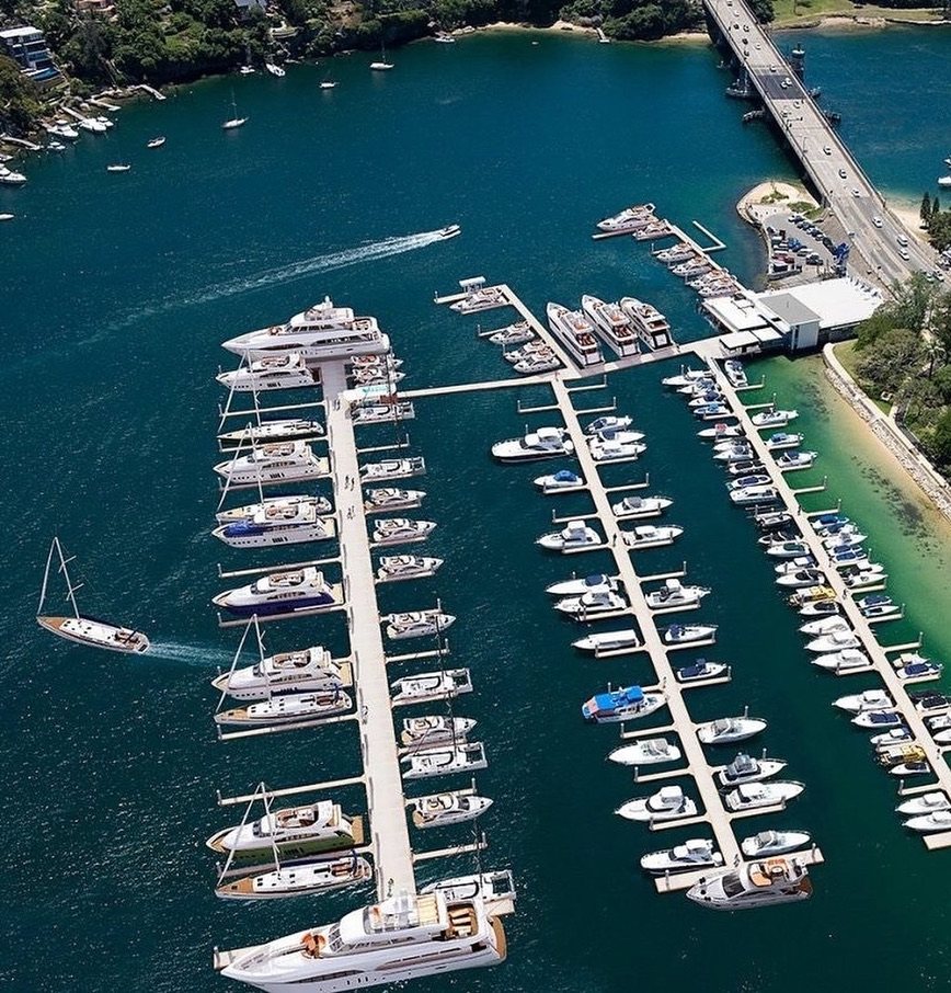 Aerial view of marina pontoons and boats beside a bridge