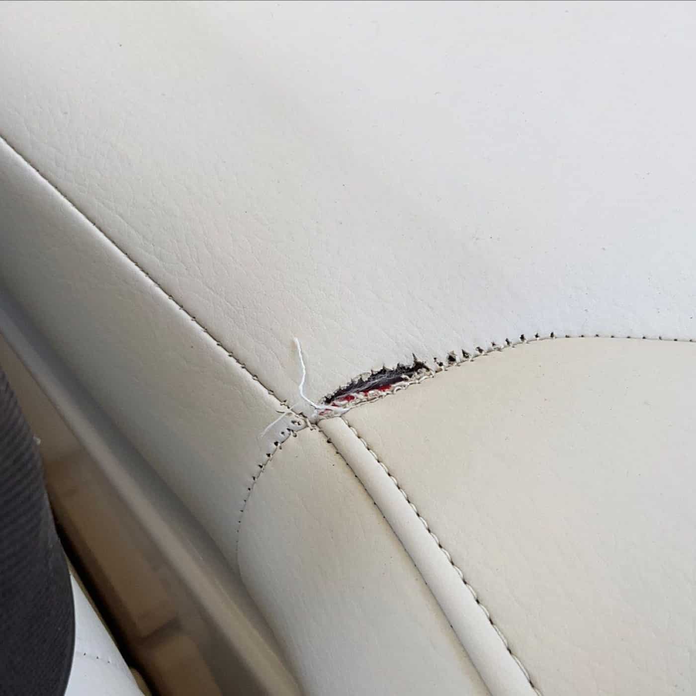 Split stitching and torn white vinyl boat upholstery